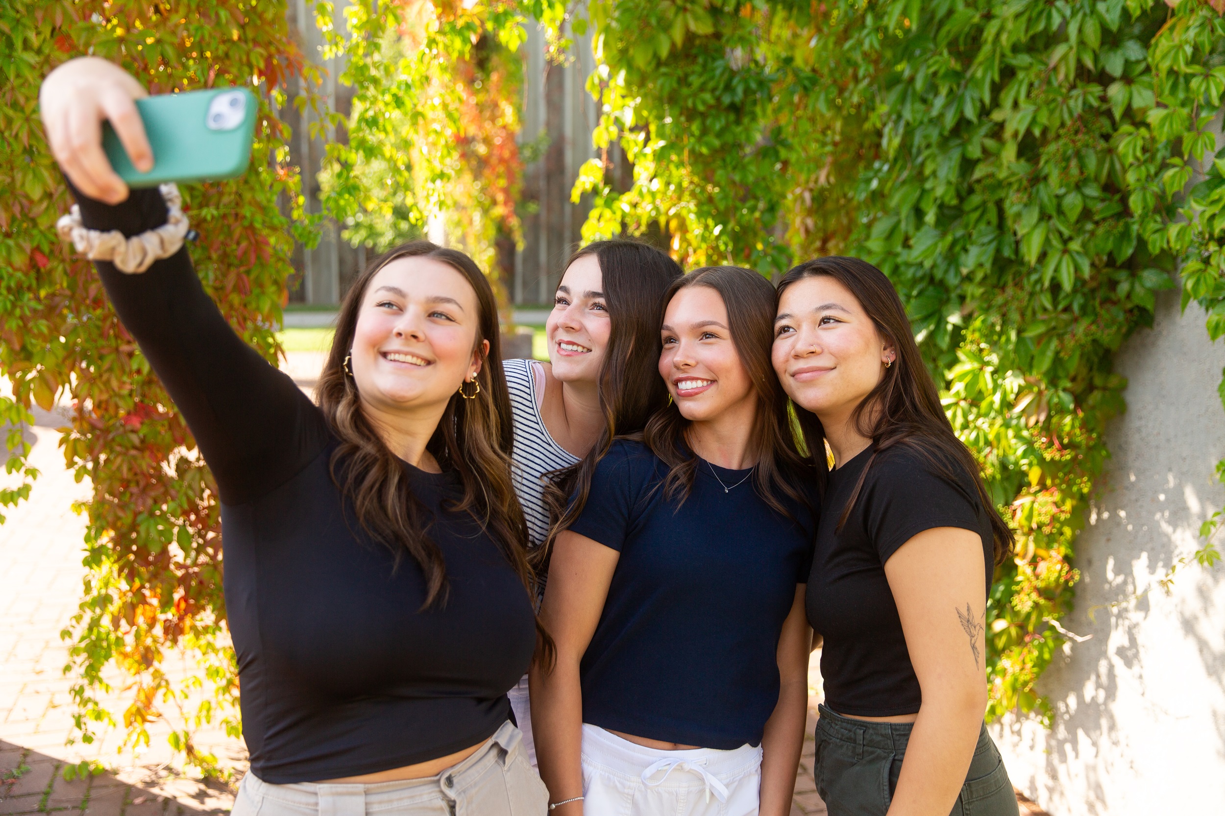 Four young women taking a selfie in the CNC courtyard in summer